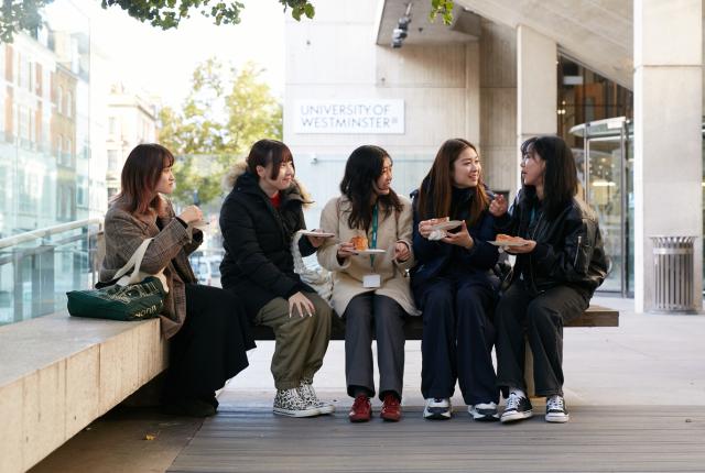 A group of four female SAF students eating pastries and enjoying conversation outside of the University of Wesminster's front entrance. 