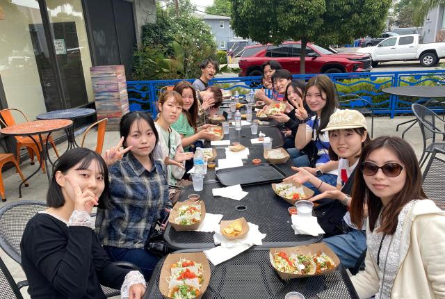 A group of students at a long table, eating tacos.