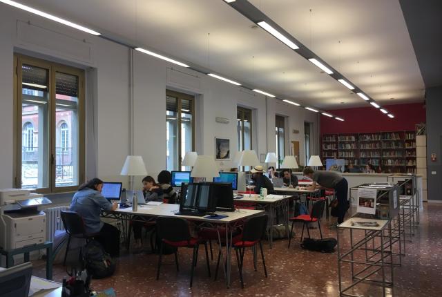 Wide view of the hub at the IES Abroad Rome Center, with students working at the tables.