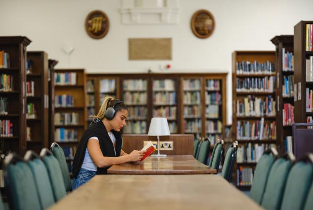 Student listening to music and reading in library of Regent's University London. 