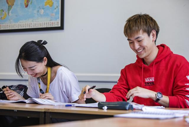 Two students in class laughing while studying. 