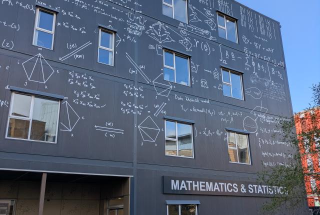 Grey "Mathematics & Statistics" building with math markings inscribed throughout. 