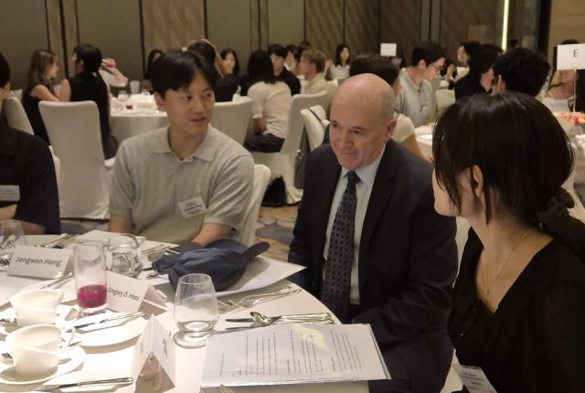 Dr. Greg Hess sitting at his table with student alumni.