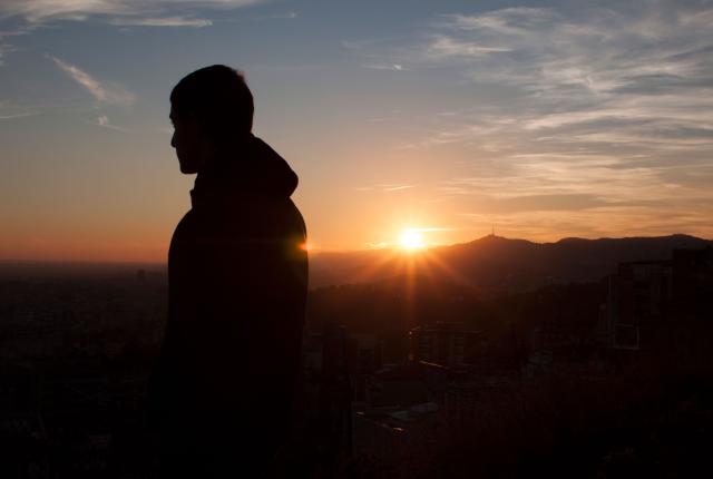 a student looks out over Barcelona from the Bunkers during sunset