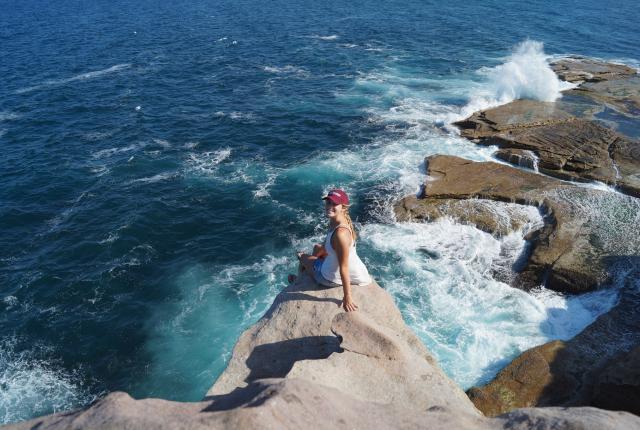 a student poses for a photo on a seaside rock in Sydney