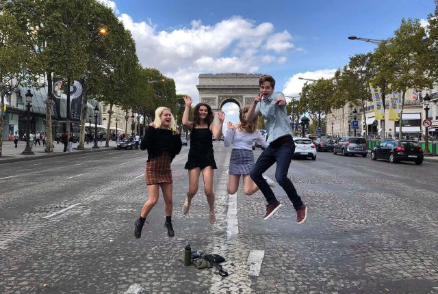 students jumping for a fun photo in front of arc de triomphe