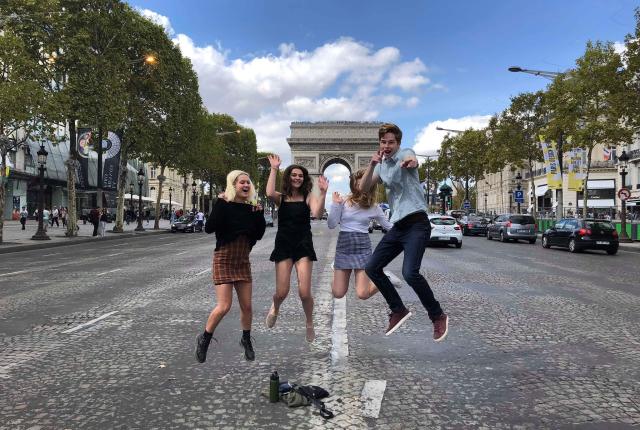 students jumping for a fun photo in front of arc de triomphe