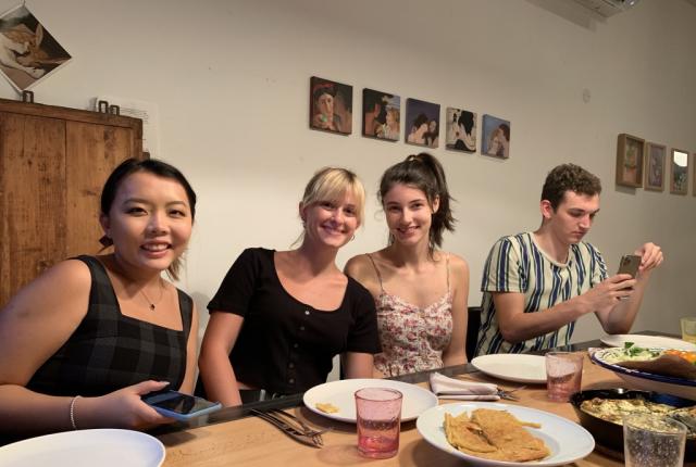 Students with their host mom seated around a dinner table at a homestay in Nice.