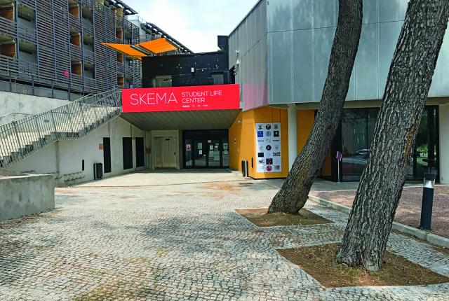 Outside of the SKEMA Student Center. There is a large staircase (left) and two large trees (right).