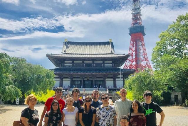 A group of students post in front of a Tokyo monument