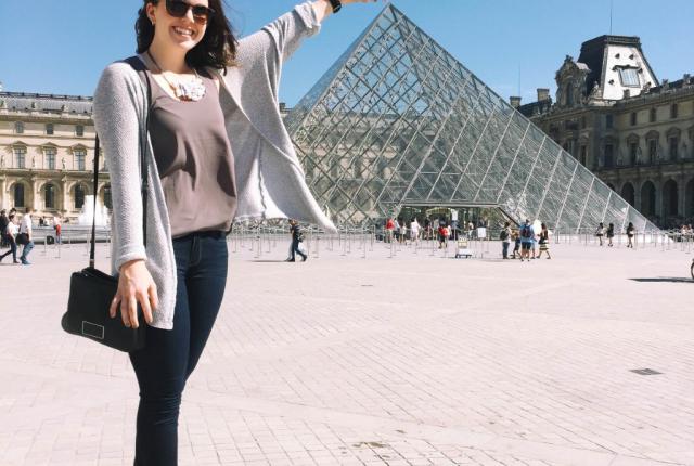 Student at an angle that looks like she is touching the top of the Louvre 