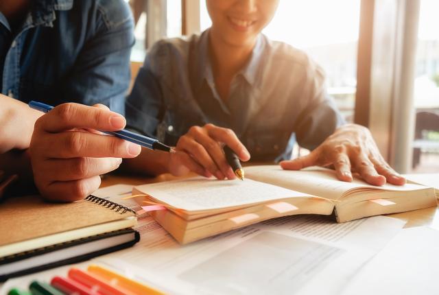 students working at a desk in front of an open book