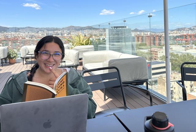 A student studding at the Social Hub in Barcelona, Spain. From the study space, there's a view of the Barcelona cityscape.