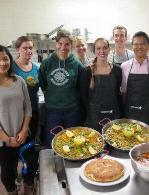 a group of students pose for a photo during a paella cooking class