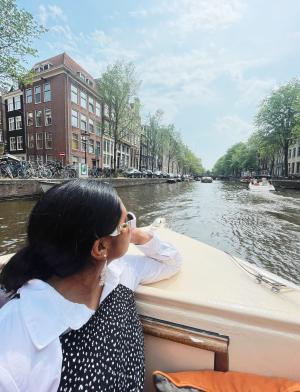 a student riding through the Amsterdam canals on a boat