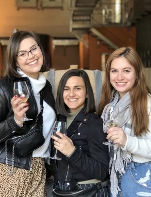 a group of students holding wine glasses and smiling at the camera