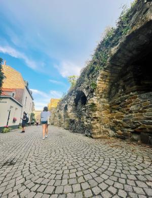 A student walks along a stone path in Maastricht on a bright day.