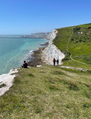 Students explore the rocky inclines off the coast of Dover on a sunny day.