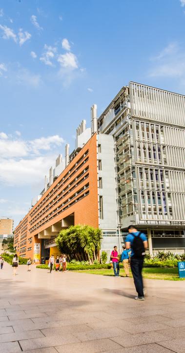 Students make their way to class on UNSW's campus, with tall brick buildings along the main walkway.