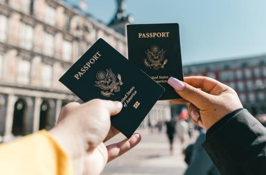 Two people holding their American passports up to the sky