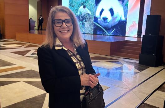 Carol Carmody smiling in front of a pictured panda.