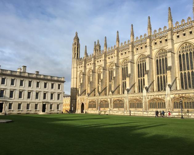 Cambridge King's College pictured on a sunny day. The building has gothic architecture and is a cream color.