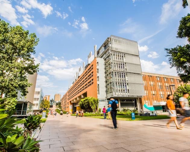 Students make their way to class on UNSW's campus, with tall brick buildings along the main walkway.