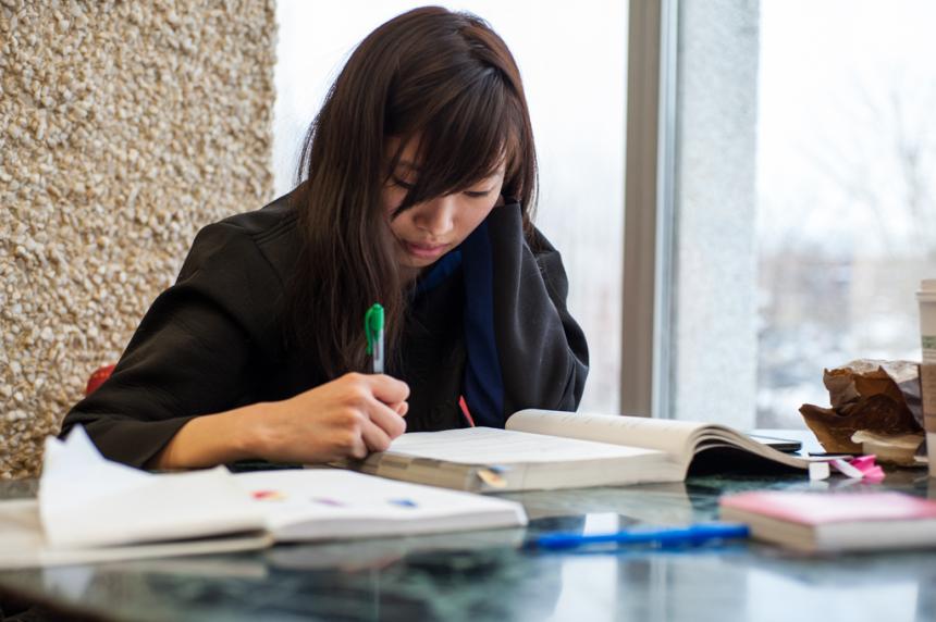 A young Korean woman studies an English language textbook for the TOEFL exam