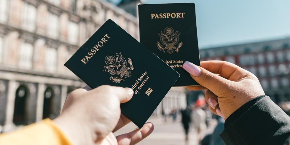 Two people holding their American passports up to the sky