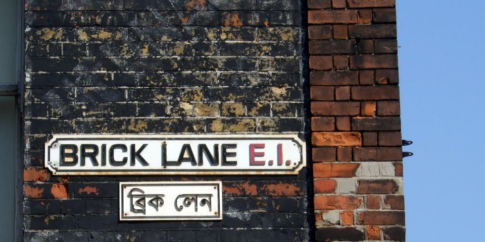 A street sign on a wall saying Brick Lane