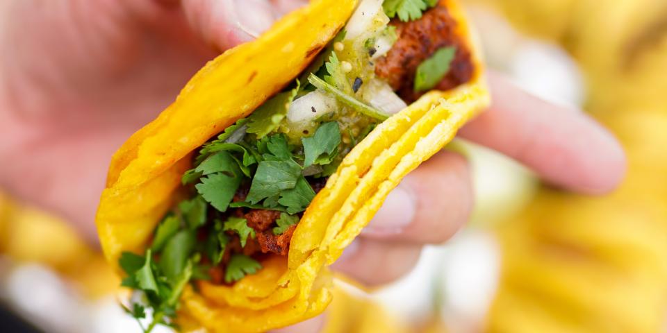 blurred background with a hand holding a taco in focus