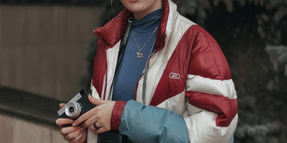 A woman wears a puffy jacket and holds an analog camera