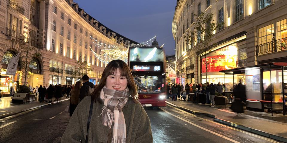 A student poses on the high street of Central London at night