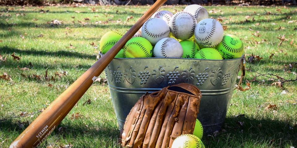 A bat, glove and basket of balls