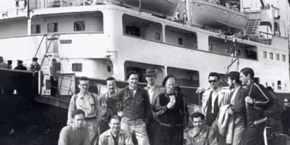 Black and white photo of an old study abroad group delegation, waving in front of a boat.
